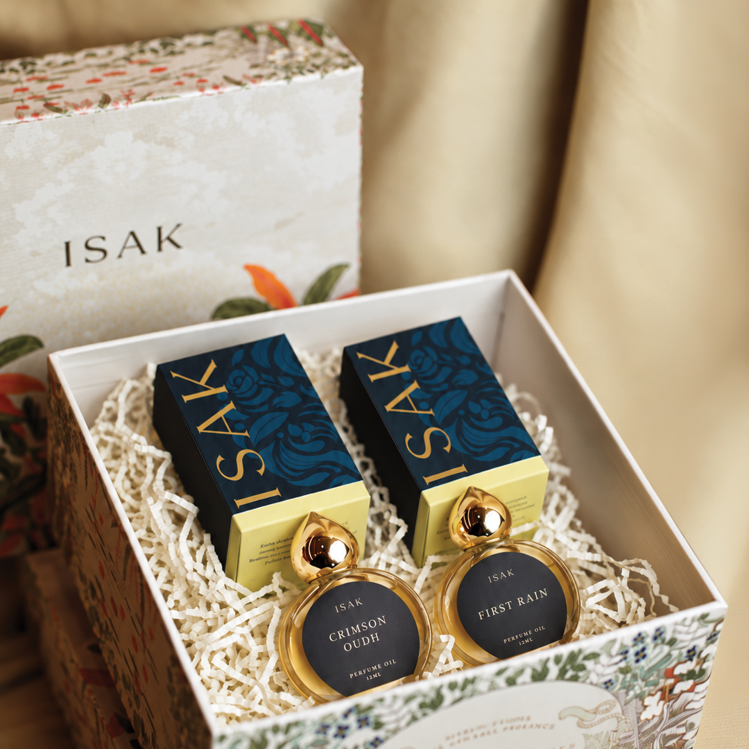 Floral gift box holding two gold attar bottles labeled First Rain and Crimson Oudh